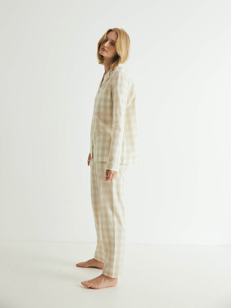A woman is standing in a white room wearing a general sleep Classic Set - Oatmeal Gingham.