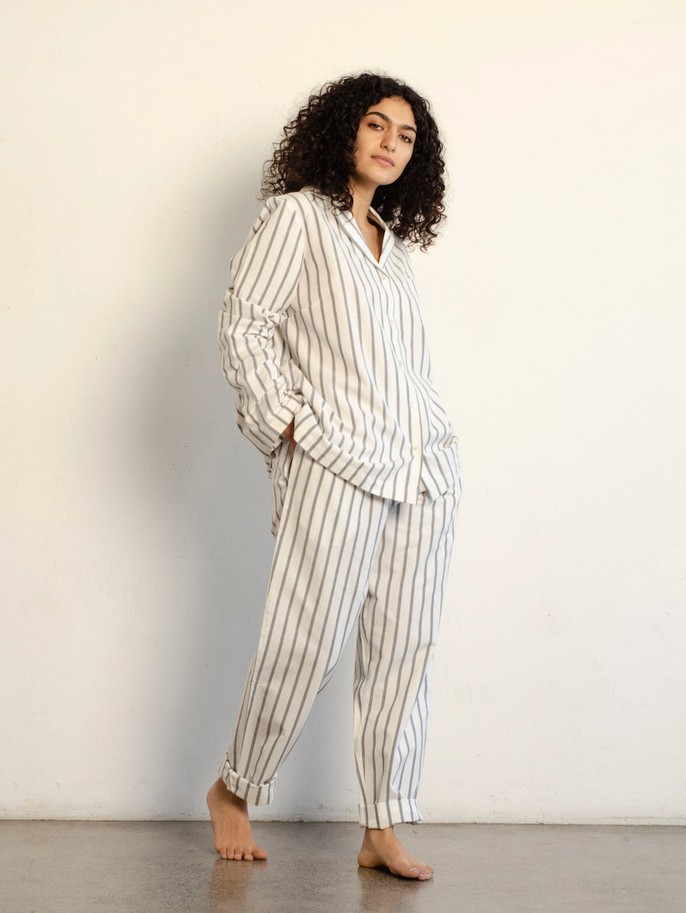 A woman wearing a white and black striped Classic Set - Stripe pajama set by general sleep.