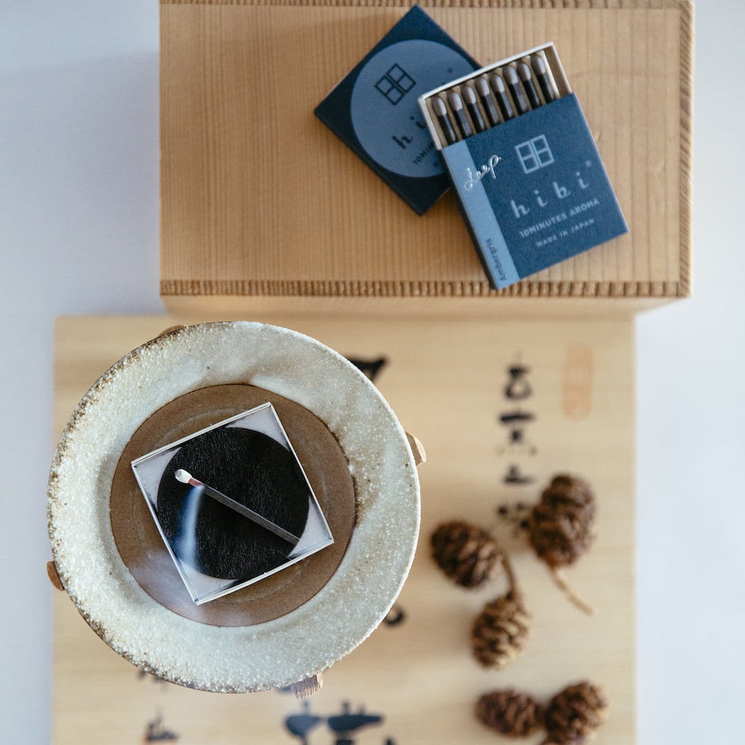 hibi Match Box Incense Deep – Ambergris and a bowl of pine cones on a wooden table.