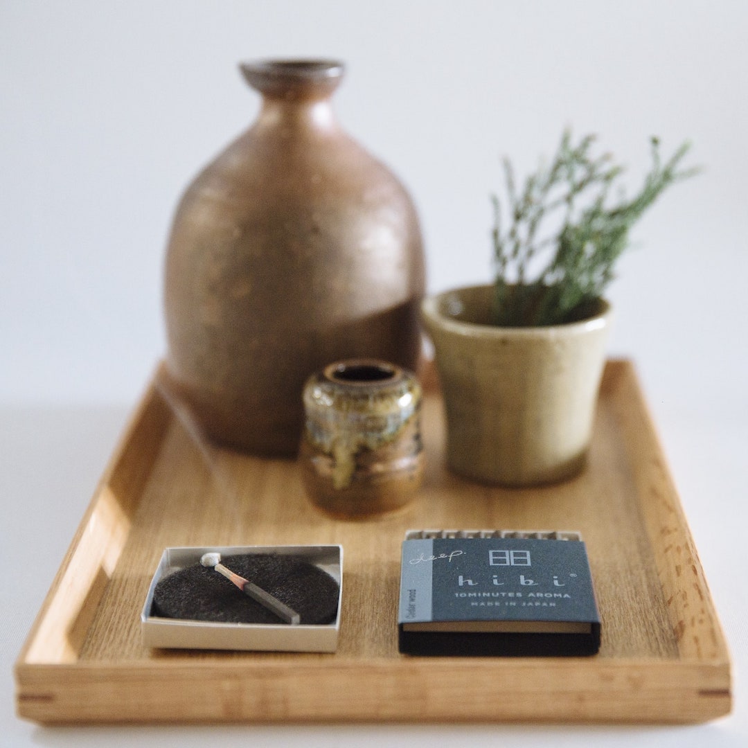A hibi wooden tray with a Match Box Incense Deep - Oak Moss and a cigarette.