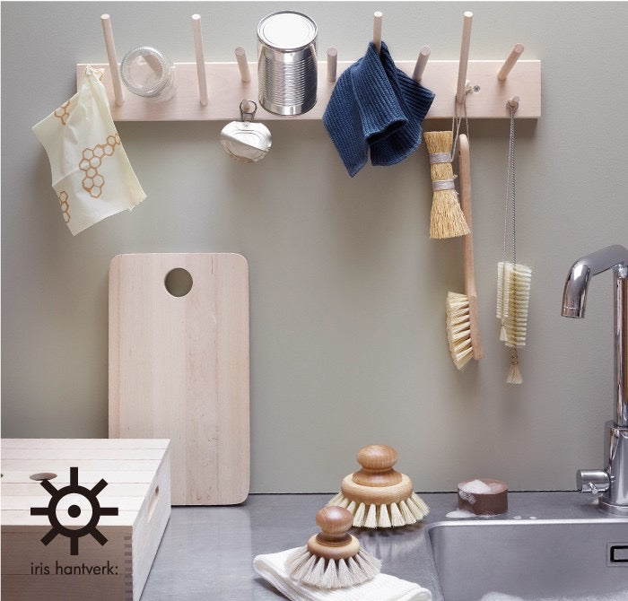 An Iris Hantverk wooden rack with a sink and Dish Brush utensils hanging on it.