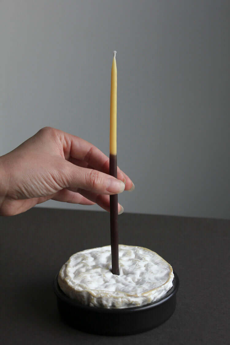 A person holding 8 Celebration Candles - Double-dipped by Wax Atelier on top of a plate.