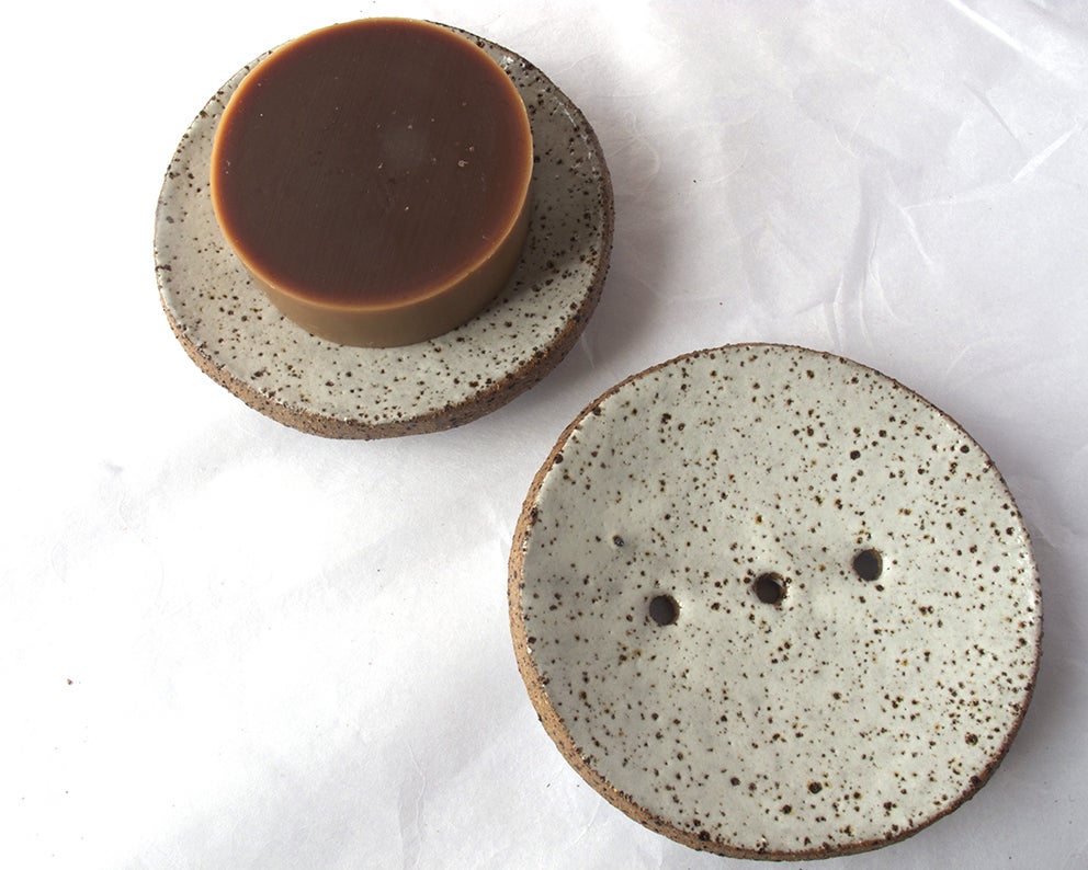 A Studio Star Round Ceramic Soap Dish - White with Black Speckle with a piece of chocolate on it.
