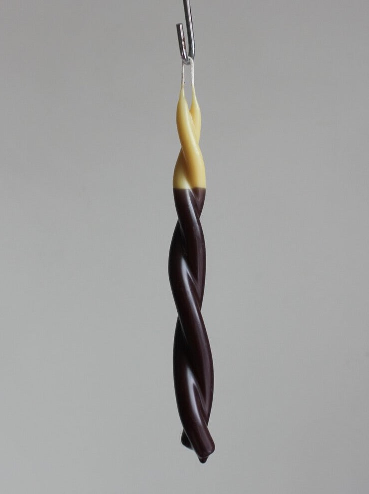 A Twisted Candle - Double-Dipped, from Wax Atelier, hanging from a wire.