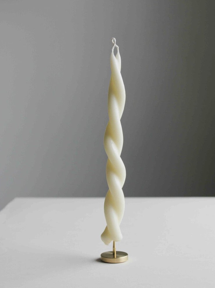 A Twisted Candle – Mother&#39;s Milk by Wax Atelier sitting on a table.
