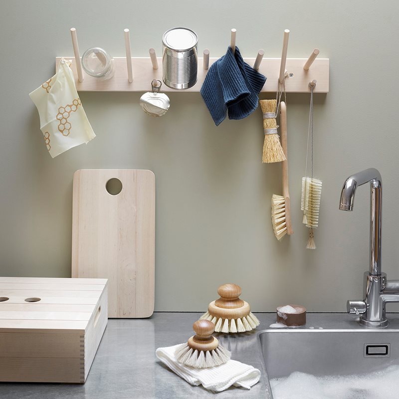 An untreated kitchen sink with versatile utensils and an Iris Hantverk Multihanger Rack – Birch hanging on the wall.