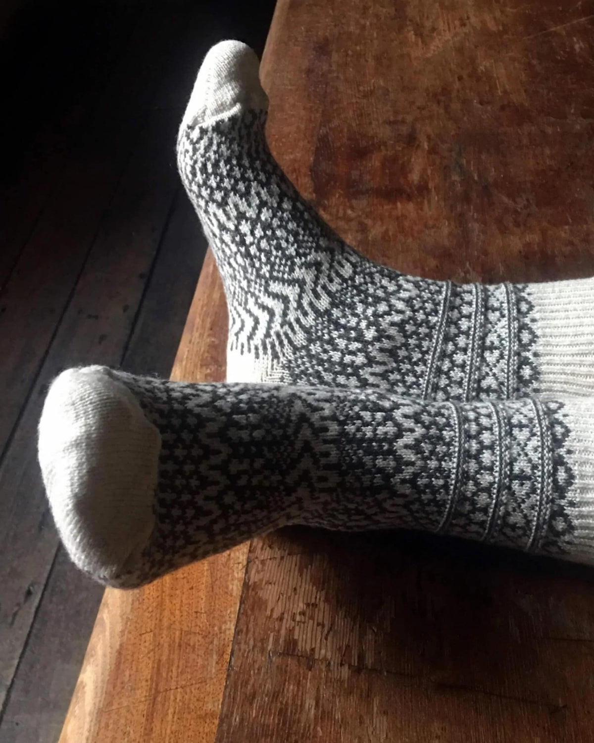 A pair of Oslo Wool Jacquard Socks – Oatmeal by Nishiguchi Kutsushita on a wooden table.