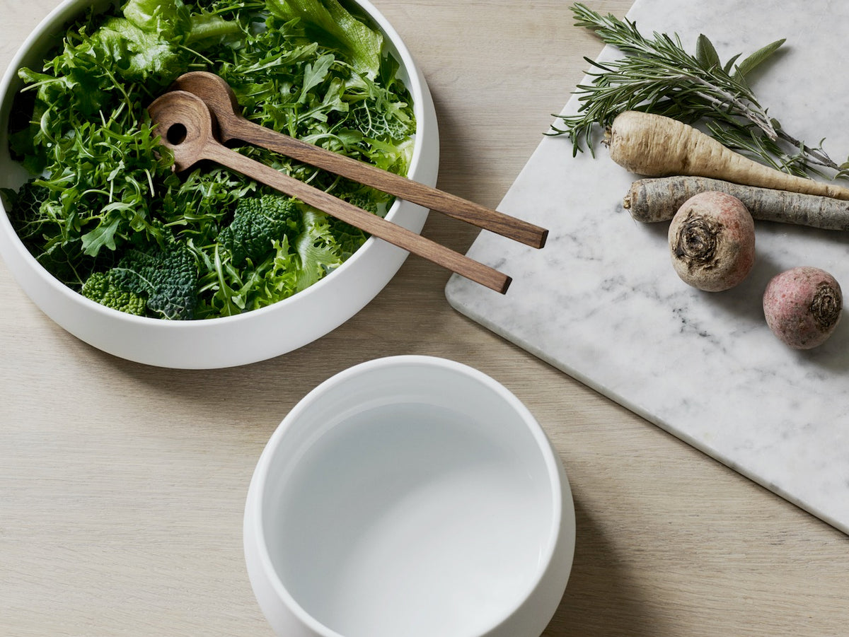 A bowl of greens and a Fulla Salad Servers by Skagerak on a table.