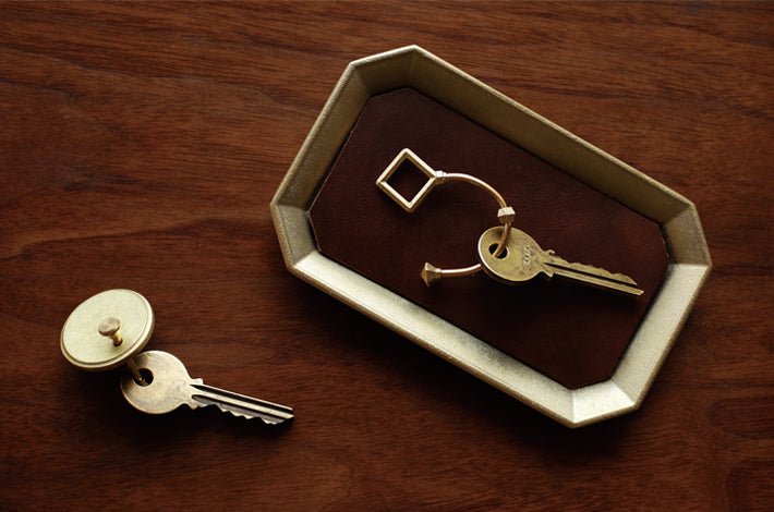 Two keys on a Stationery Tray – Solid Brass by Futagami on a wooden table.