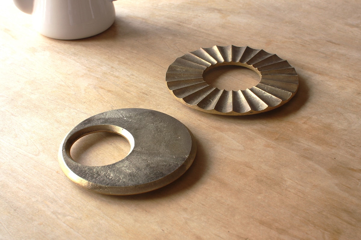 A cup of Moon Trivet – Solid Brass coffee on a wooden table by Futagami.